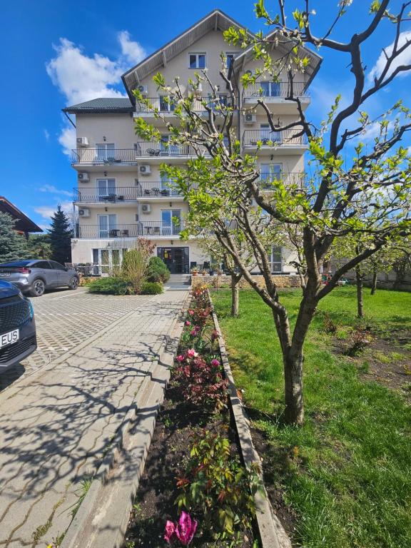 a tree and flowers in front of a building at Daiana Residence Turda in Turda