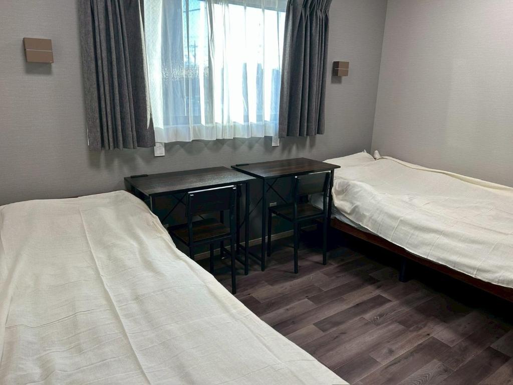 a room with two beds and a desk and a window at Stella Casa in Gotemba