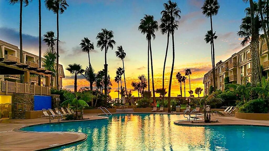 a swimming pool in a resort with palm trees at SolMar Breeze - 1BR Condo at North Coast Village - Heated Pools, Hot Tubs & Steps to Beach, Oceanside Harbor and Pier in Oceanside