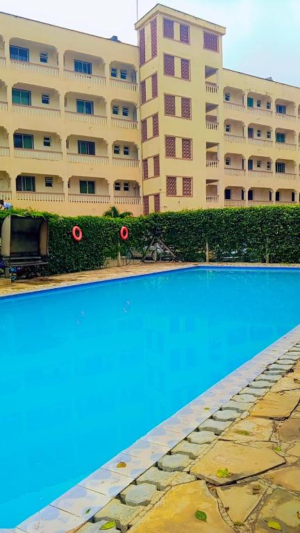 a swimming pool in front of a large building at Bamburi Mombasa two bedrooms at Cutraz homes villa 003 in Mombasa