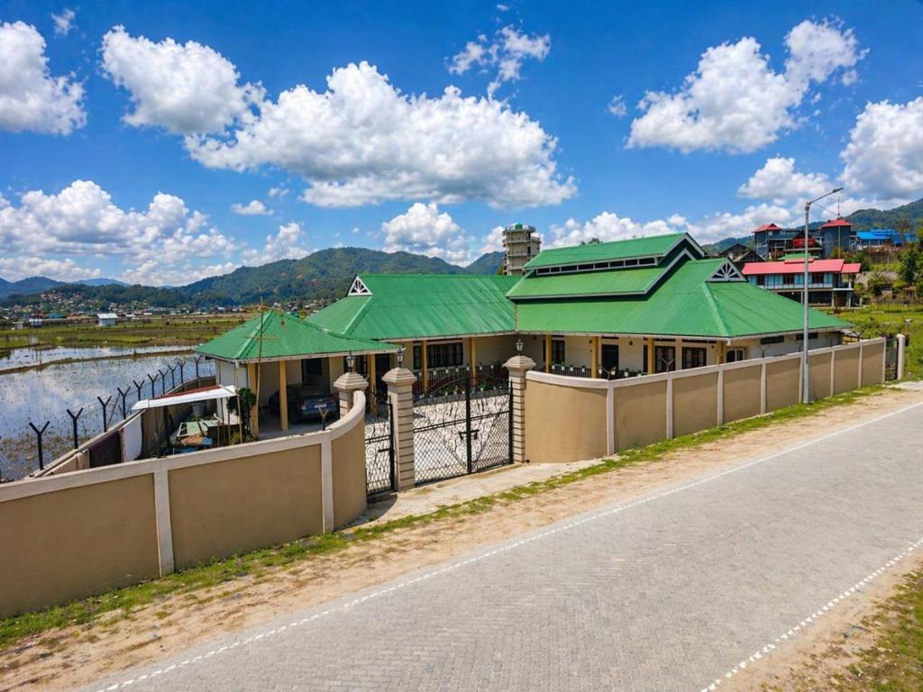 a building with a green roof on the side of a road at Valley Roots Homestay in Ziro