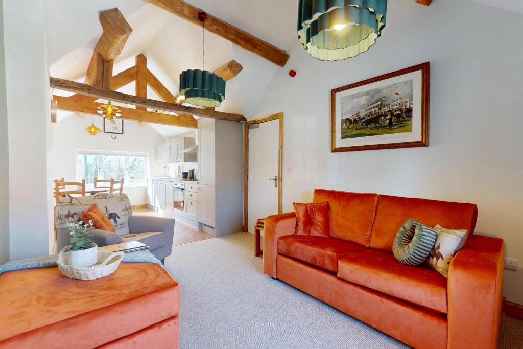 a living room with a red couch and a table at The Winners Enclosure - Country Flat Above a Village Pub in Shrewsbury