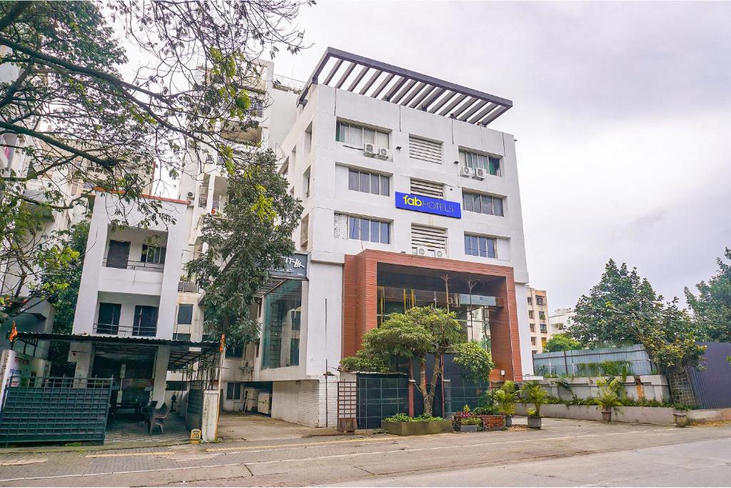 a tall white building with a blue sign on it at FabHotel Vardhan Plaza in Pune