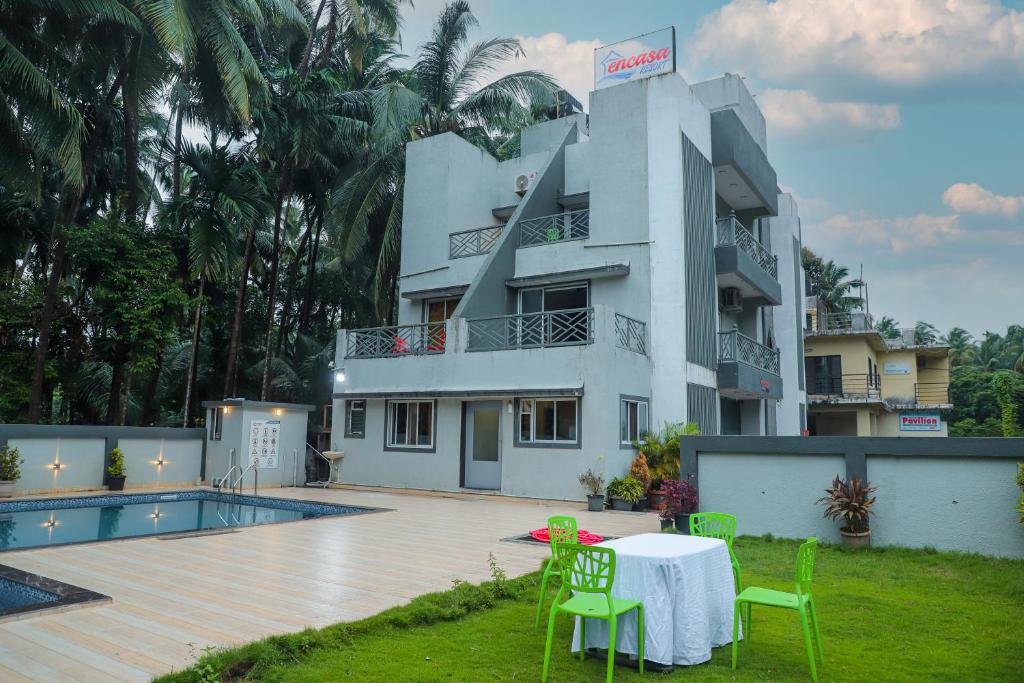 a white building with a table and chairs in front of it at Encasa Resort in Nagaon