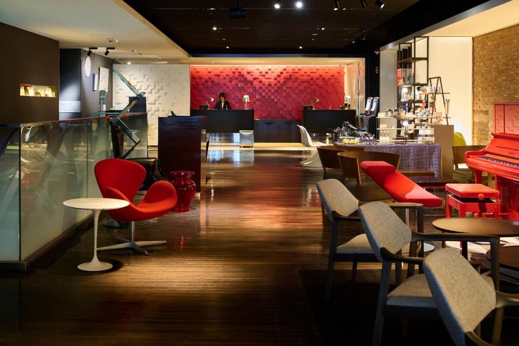 ein Restaurant mit roten Stühlen und Tischen und einer Bar in der Unterkunft Cross Hotel Sapporo in Sapporo