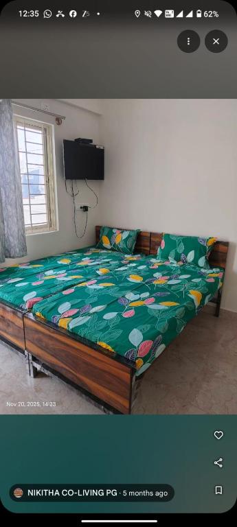 a bedroom with a bed with a green comforter at nikitha co living pg in Bangalore