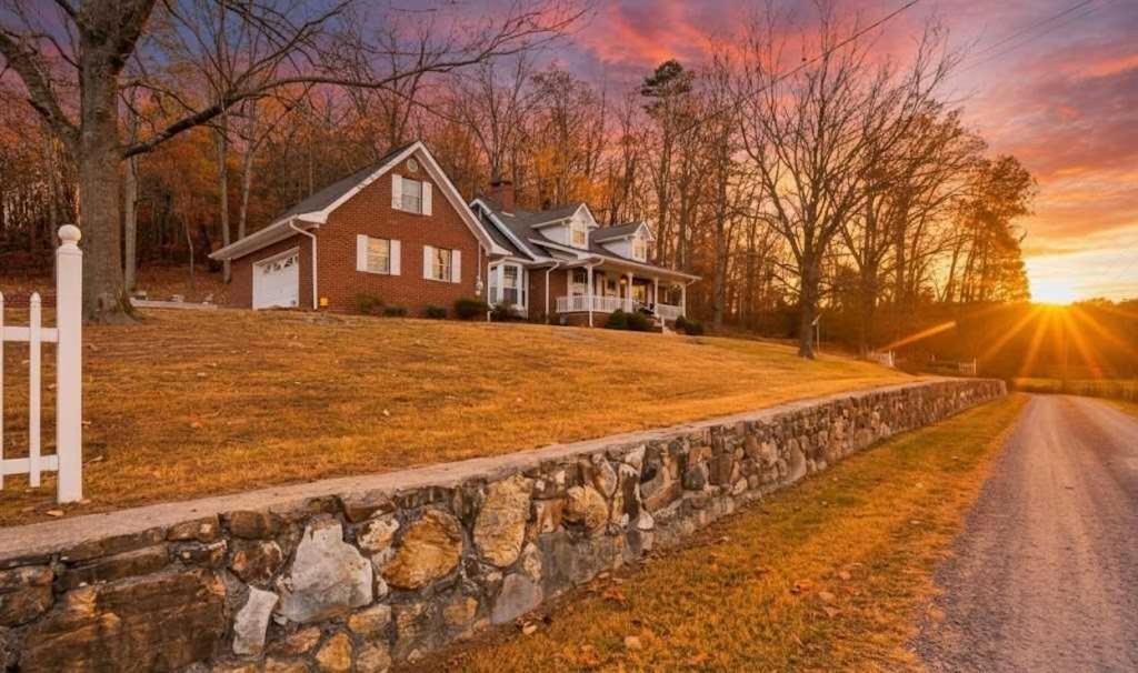 a house on a hill with a stone wall at Countryside Retreat with Views! Red Clay Farmhouse in Cleveland