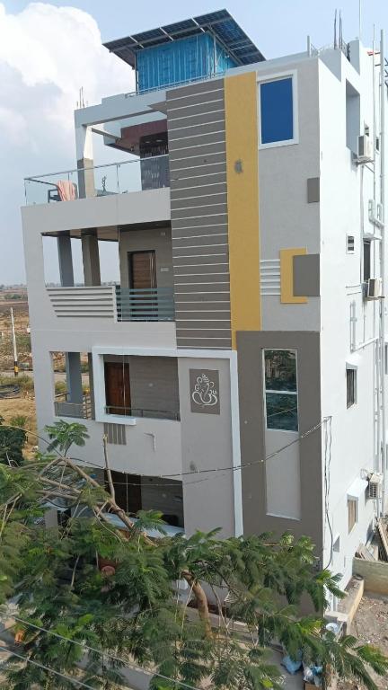 a tall white building with a yellow and white at Vasavi Homes in Mādhavaram