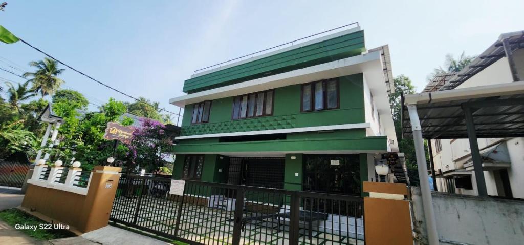 a green and white house with a black fence at Dreamers Lounge in Trichūr