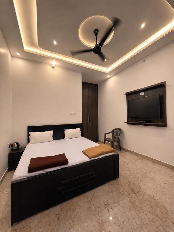 a bedroom with a bed with a ceiling fan and a flat screen tv at Vijay palace 850 meter away from Ram mandir in Ayodhya