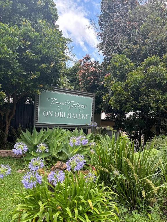 a sign in a garden with purple flowers at Tranquil Getaways On Obi Maleny in Maleny