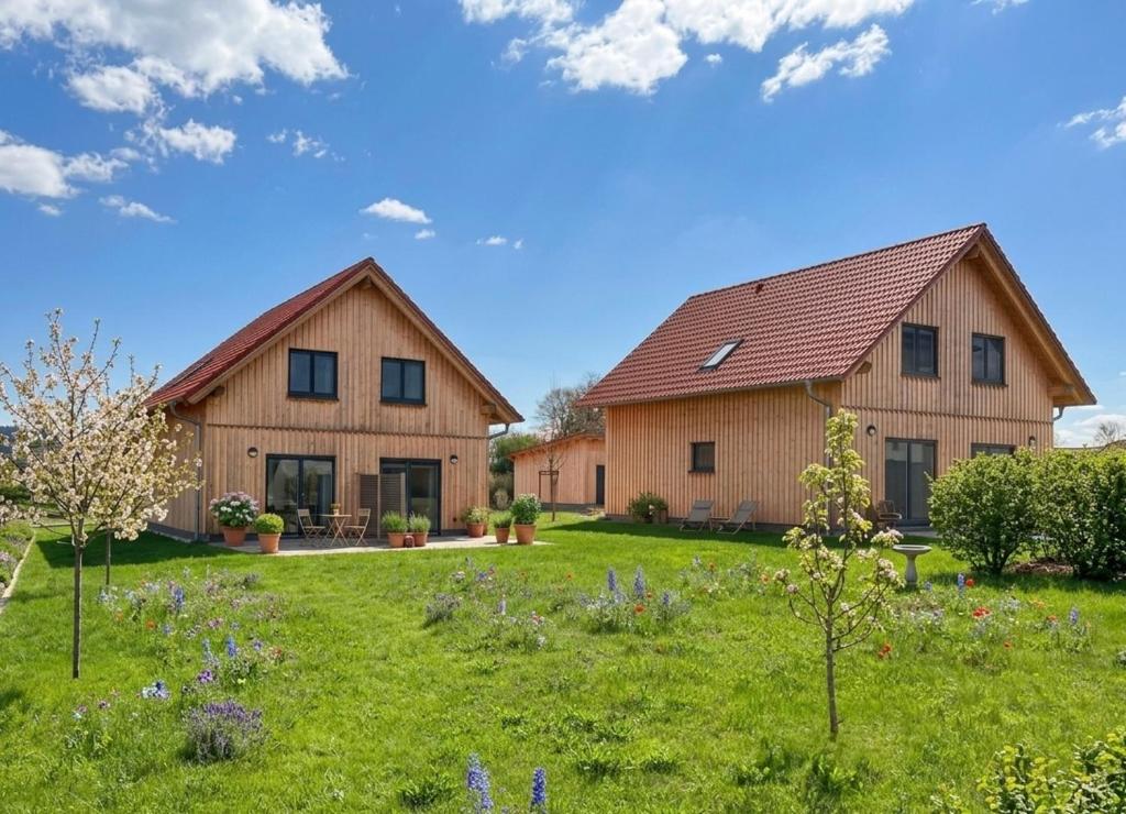 two houses in a field with flowers in the yard at Familiengasthof Schaller in Floß