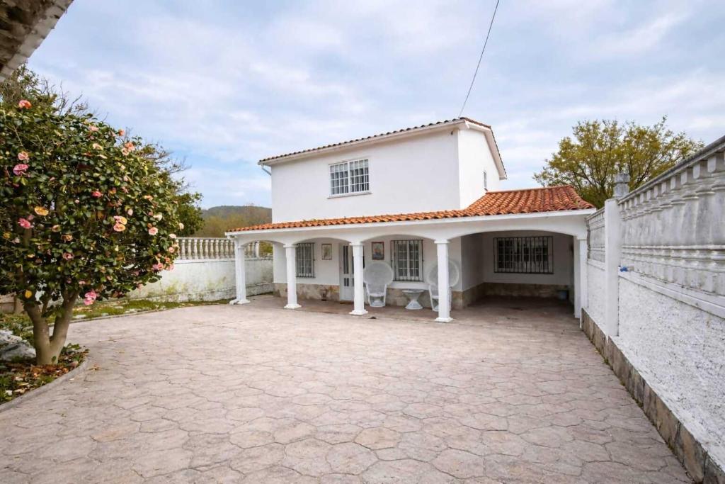 a white house with a patio and a fence at Chalet cerca de la playa de Esmelle in Pedreira