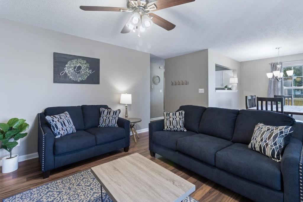 a living room with two blue couches and a ceiling fan at Crossroads Cottage l Grill & high speed internet in Chattanooga
