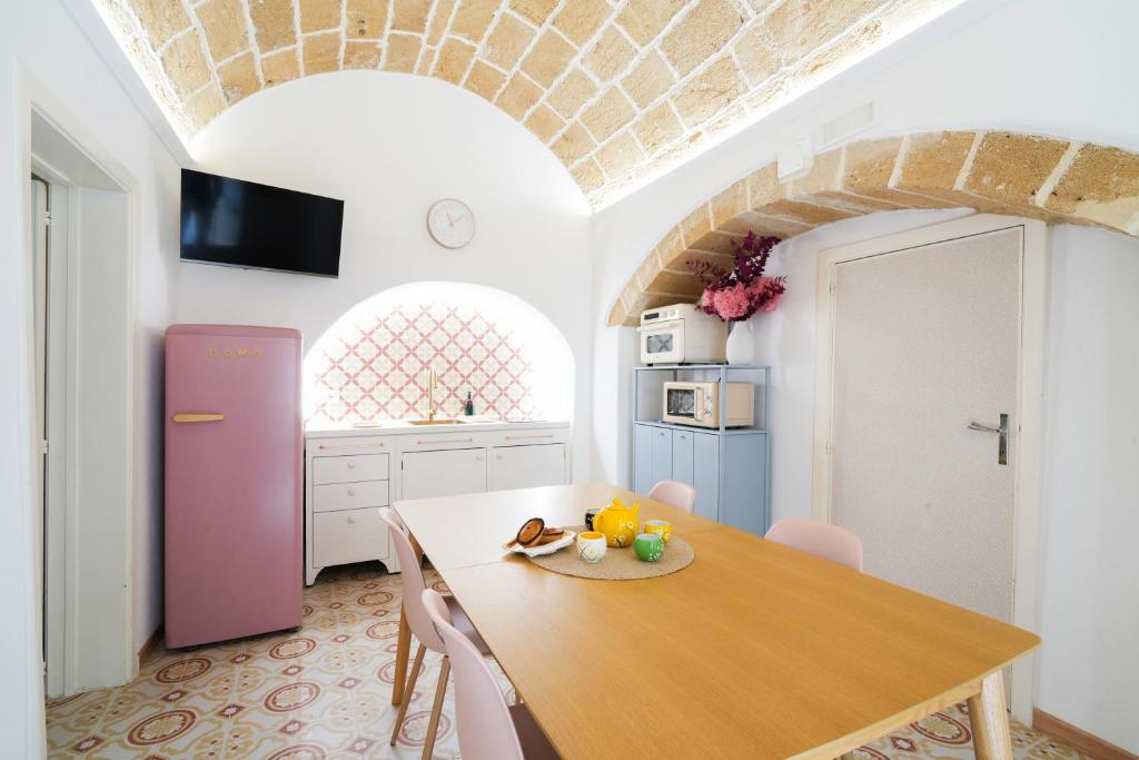 a kitchen with a wooden table and a pink refrigerator at Pantabrì - Casa Tipica su Mare nel Centro Storico di Gallipoli in Gallipoli