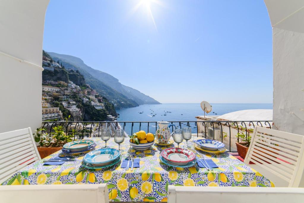 a table with plates and glasses on a balcony with a view at Estate4home - Casa Bouganville in Positano