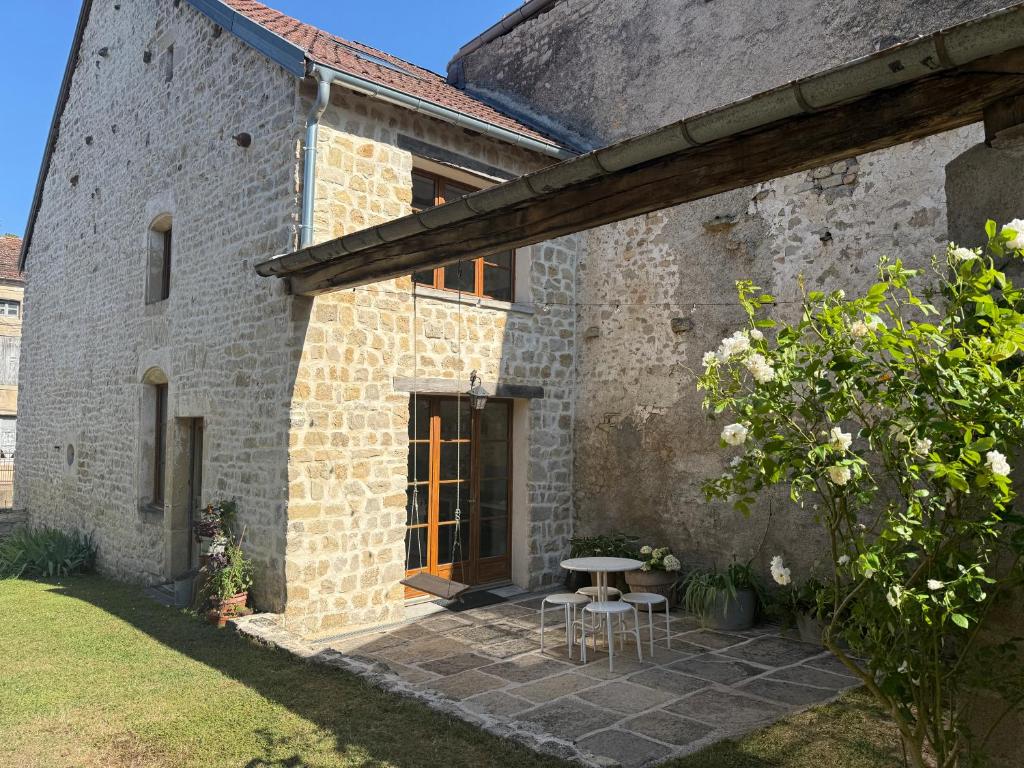 an external view of a stone house with a table and chairs at L'Epicerie in Melay
