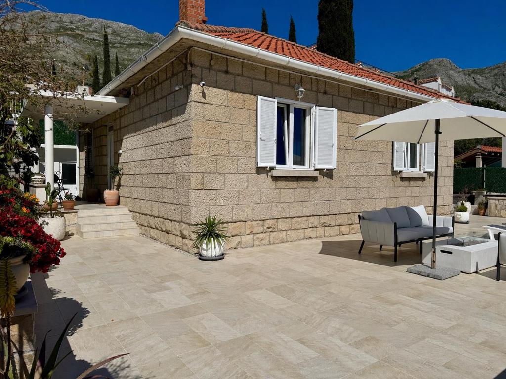 a patio with a chair and an umbrella and a house at Holiday Home Lungo Mare in Mlini