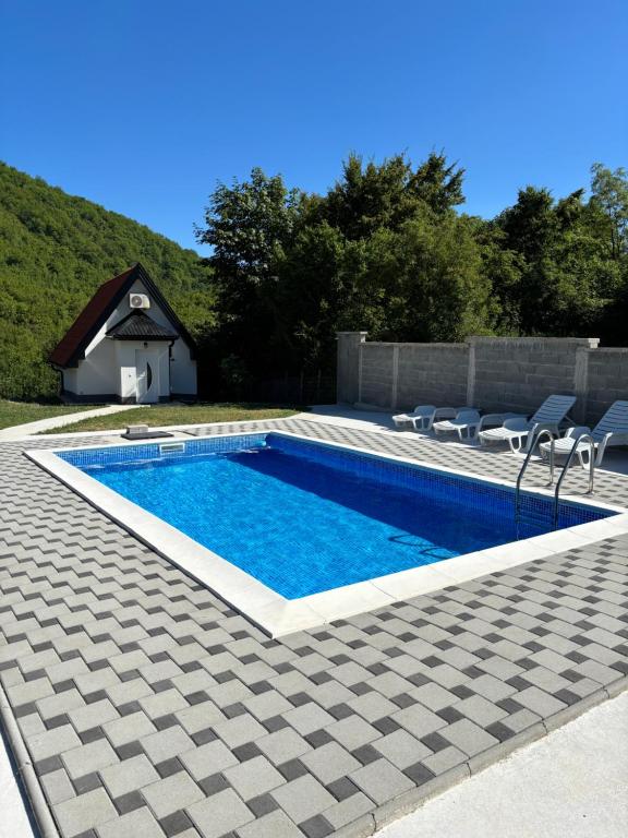 a swimming pool with chairs next to a house at Vikendica Casa Verde in Konjic