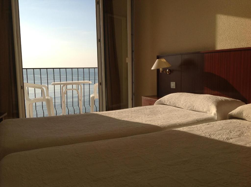 two beds in a hotel room with a view of the ocean at Hotel San Miguel in Altea