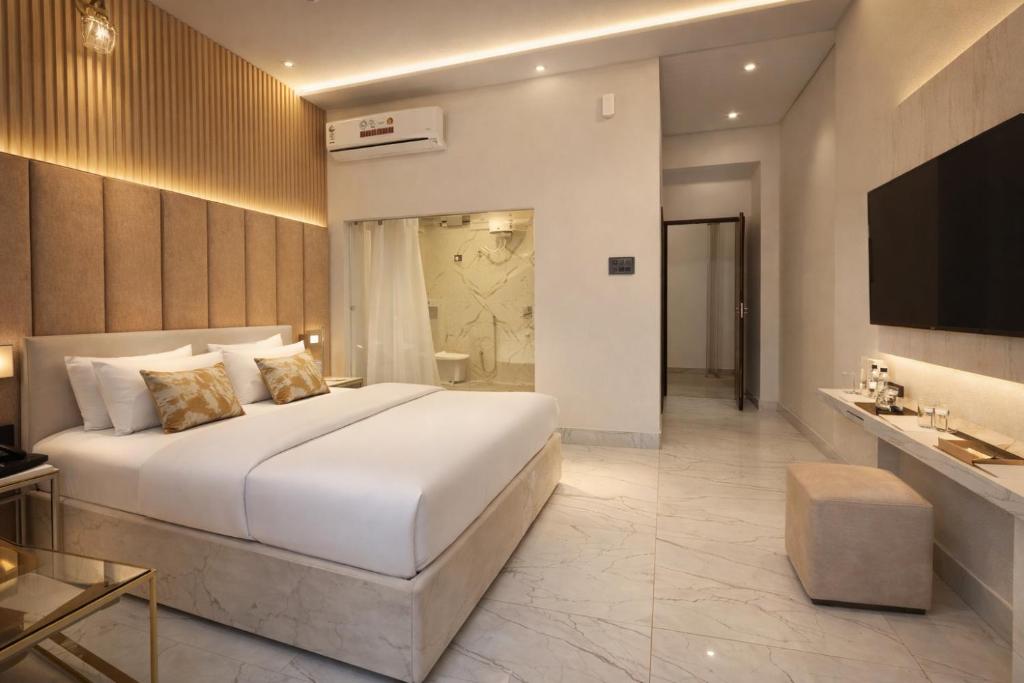 a bedroom with a large white bed and a bathroom at Trishul inn in Rudraprayāg