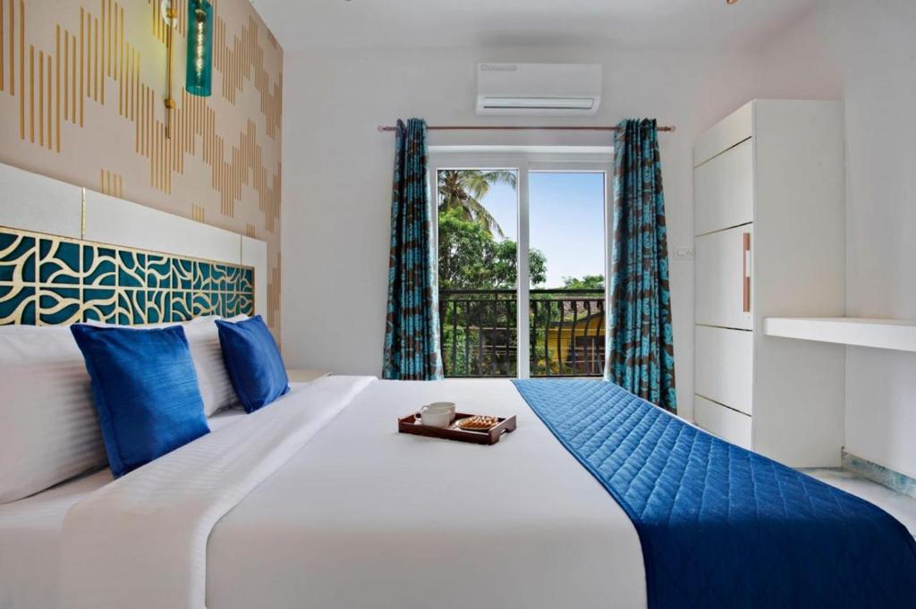 a bedroom with a large white bed with blue accents at Sea Cliff in Calangute