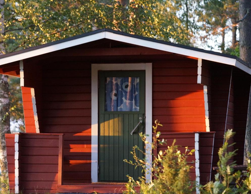 a small red house with a green door at Kyyjärvi Camping And Hotels Oy in Kotkaniemi
