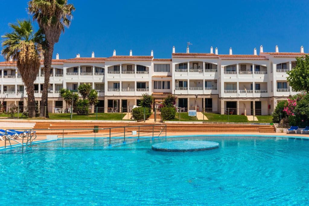a large swimming pool in front of a large building at Apartamento en Cala'n Blanes in Ciutadella