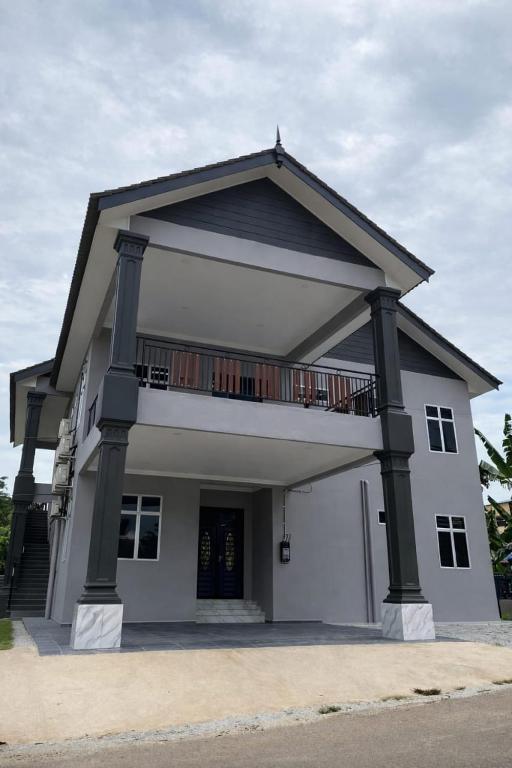 a white house with a balcony on top of it at UZ Jerteh Inn in Jertih