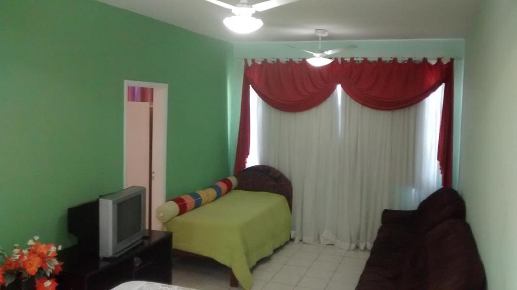 a living room with a couch and a tv at Mares do Sul Apartment in Praia Grande