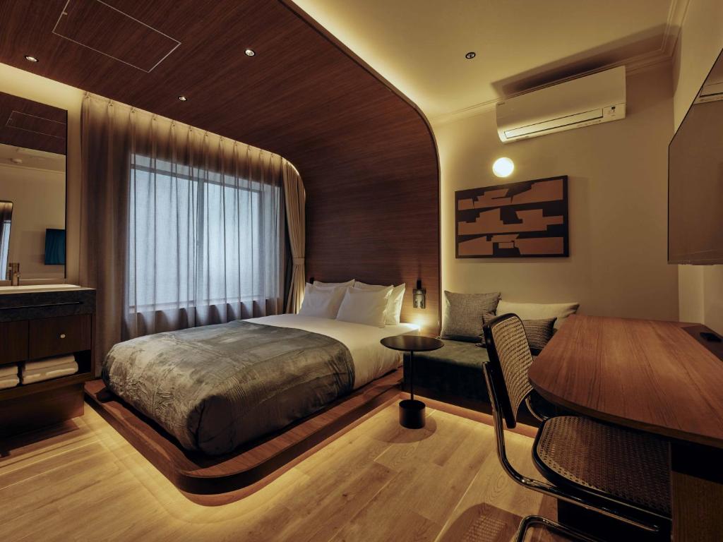 a bedroom with a bed and a desk and a piano at illi Hotels Lume Shibuya in Tokyo