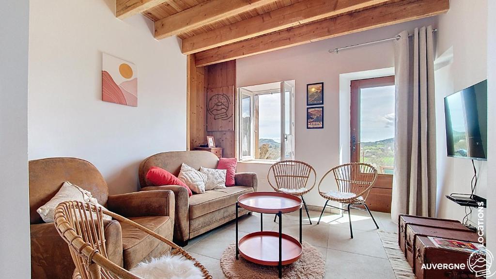 a living room with a couch and a table and chairs at Aux Marches du Château in Murol