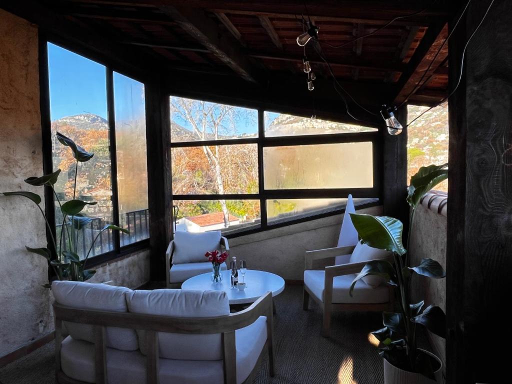 a room with a table and chairs and windows at L'Attrape-Rêves in La Gaude