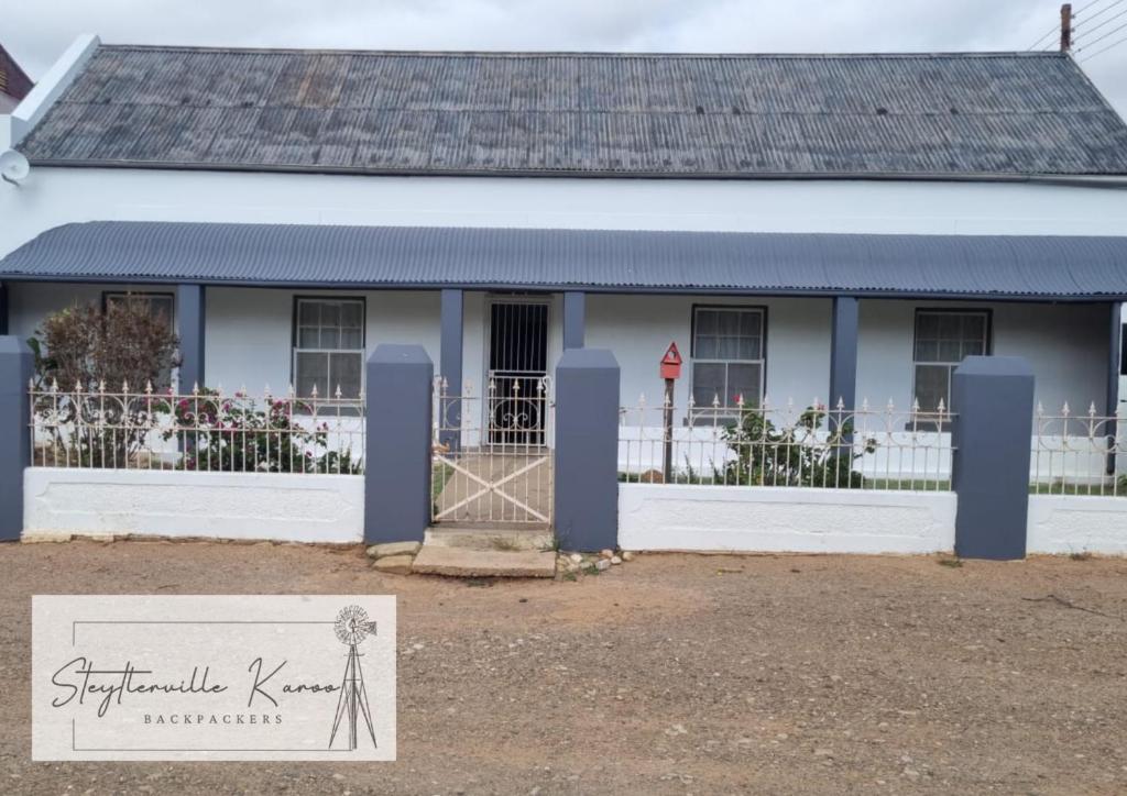 a white house with a sign in front of it at Steytlerville Karoo Backpackers in Steytlerville