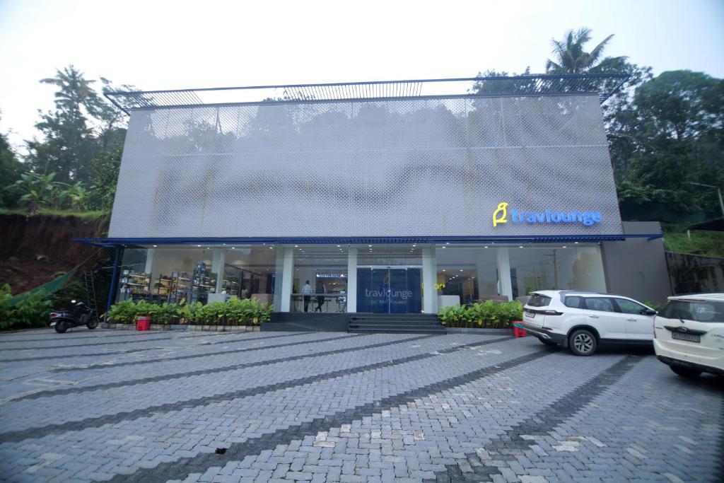 a building with cars parked in a parking lot at Travlounge Adimali in Chillithodu