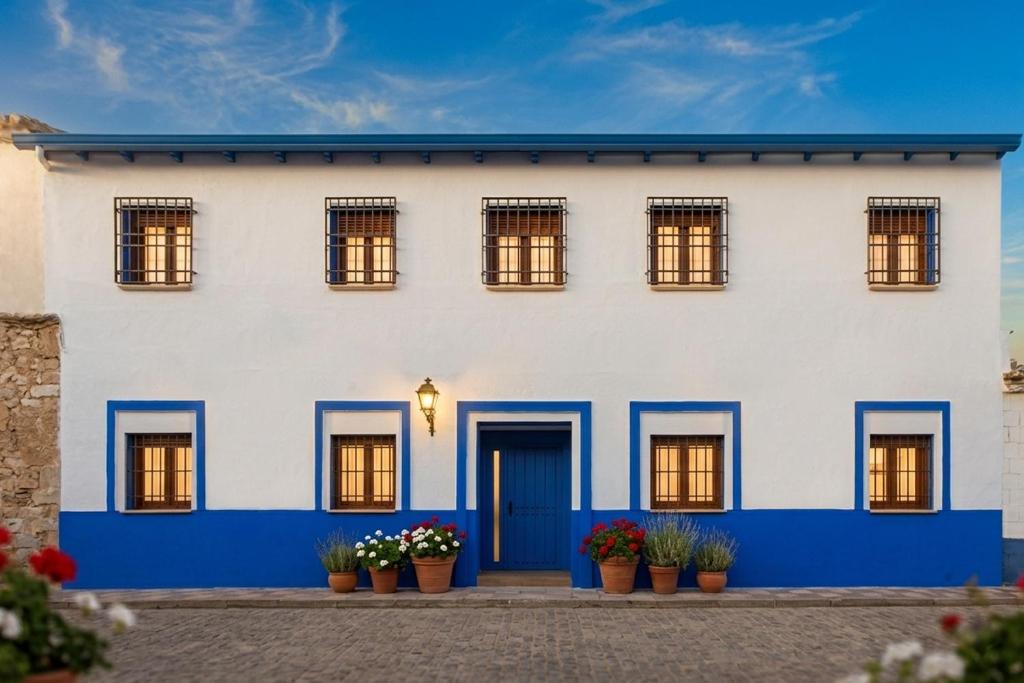 a white house with blue doors and potted plants at Casa Rural La Posada del Quijote in Puerto Lápice