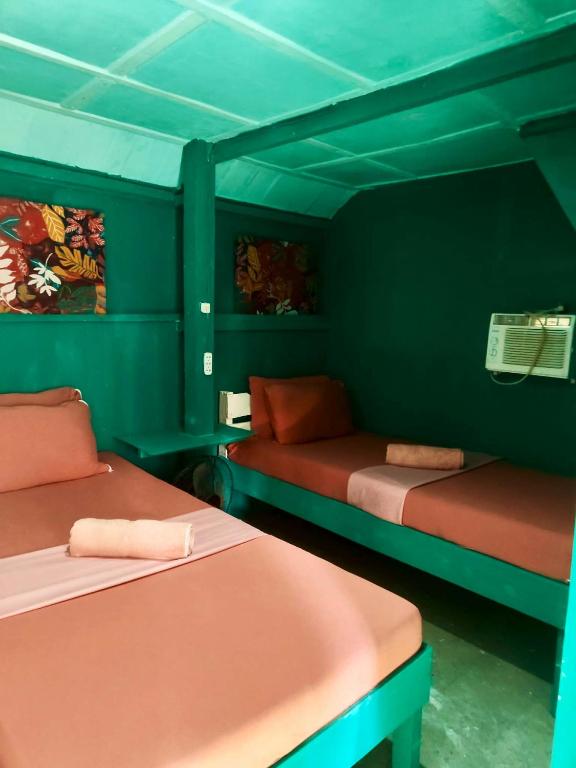 two beds in a room with green walls at MyLove Siargao Village in General Luna