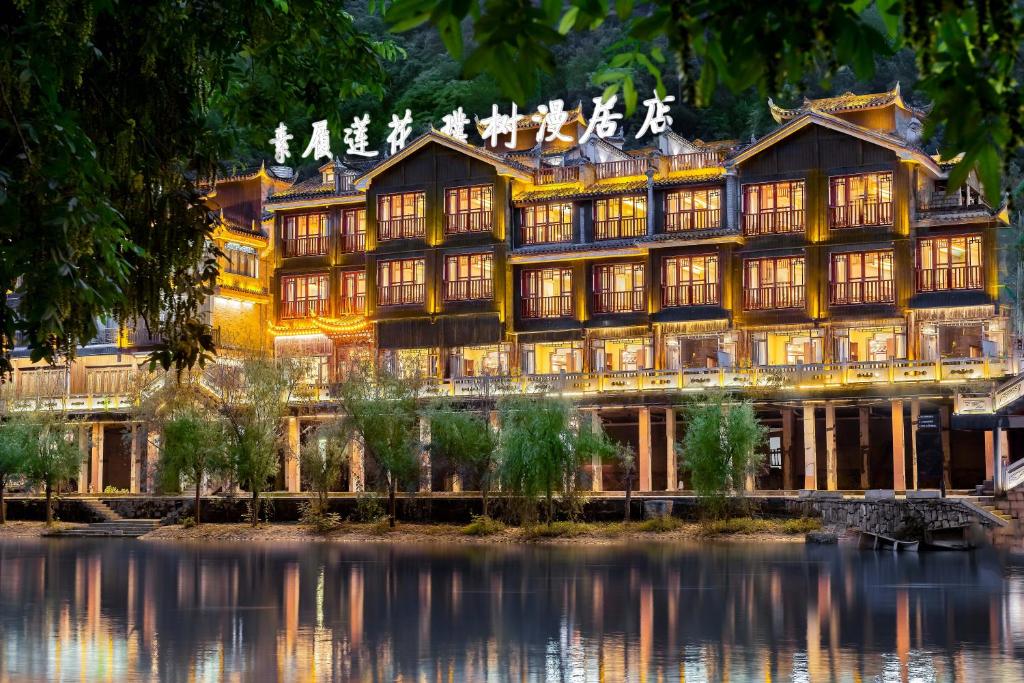 a large building with a pond in front of it at Phoenix River View Hotel-Free pick up service from Railway in Fenghuang County
