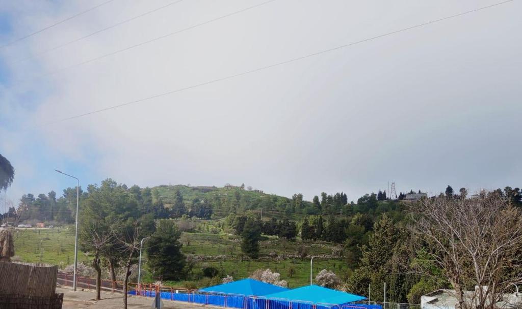a view of a hill with a blue fence at Neoth Deshe 770 in Safed