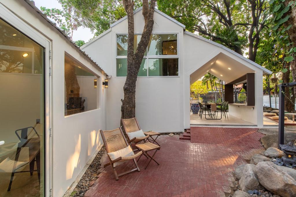 a white house with chairs on a brick patio at OHASIS by OH Hotels in Bangkok