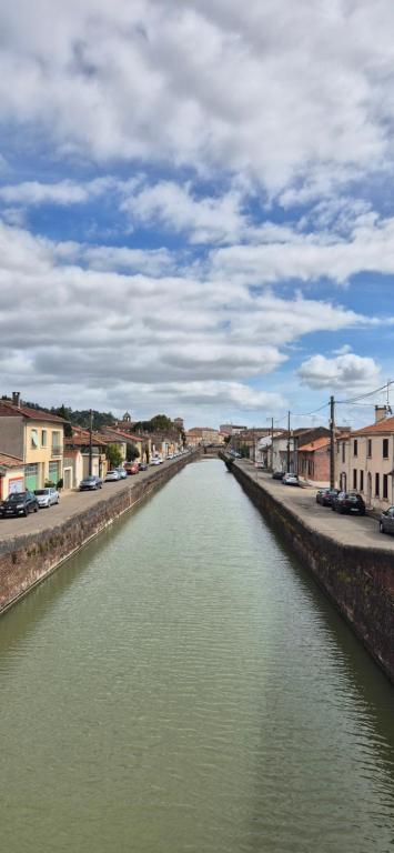 a canal of water with buildings and cars on a street at Maison canal - Douceur Occitane in Moissac