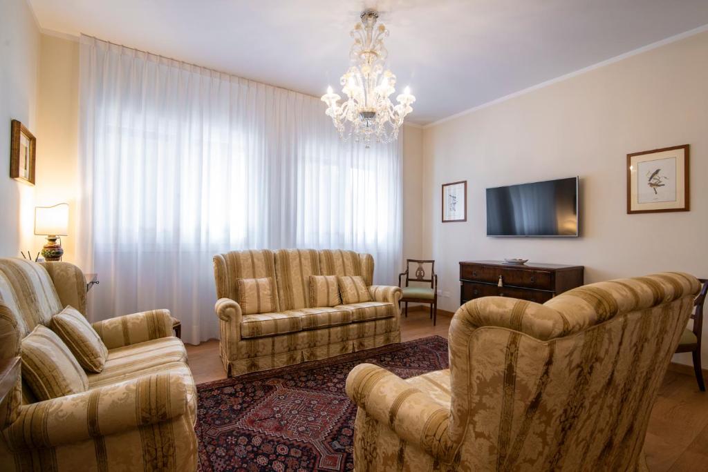 a living room with chairs and a tv and a chandelier at Residenza Maria Luisa in Padova