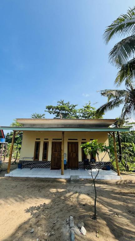 a house with a palm tree in front of it at Bintang Sawarna 2 By ARBA in Sawarna