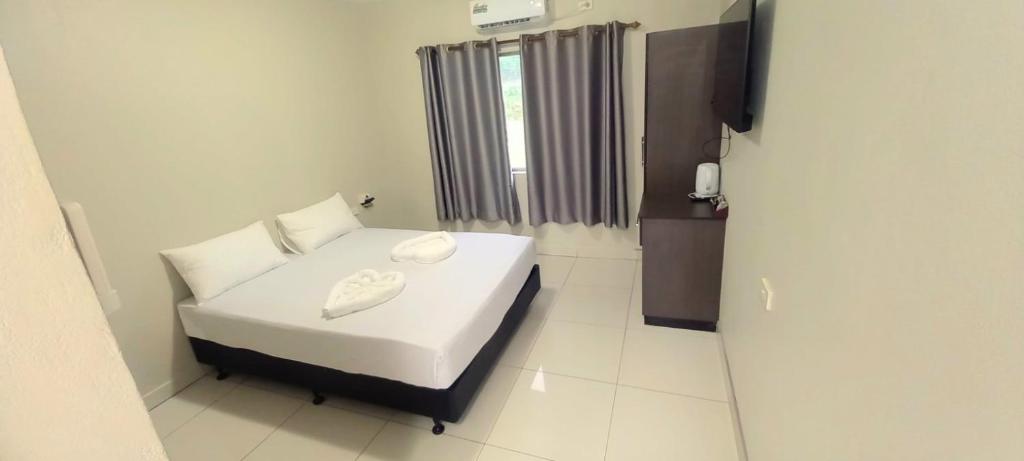 a small bedroom with a white bed and a window at Red Palm Hotel in Suva