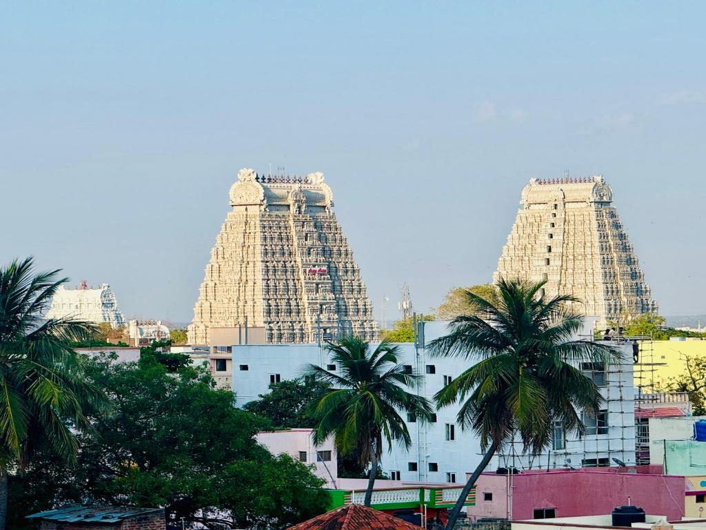 two tall buildings in a city with palm trees at Hotel SK Temple View in Tiruvannāmalai