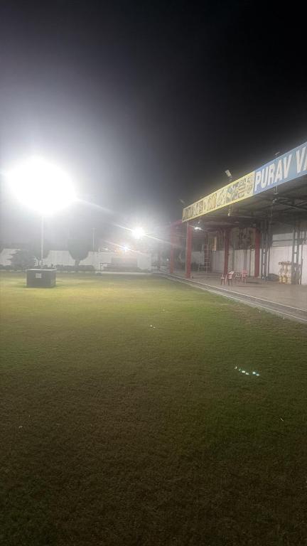 a soccer field at night with the lights on at Purav Hotel in Kharkhauda