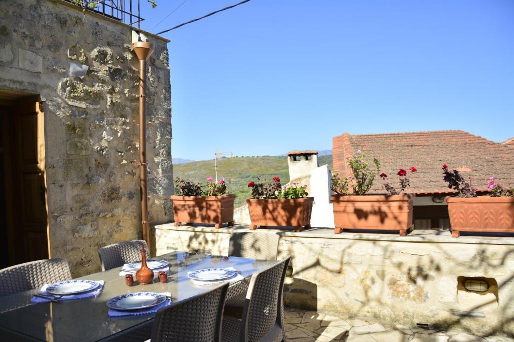 a table and chairs on a patio with potted plants at Roukouneli Traditional Stone House - Terrace & BBQ in Arménoi