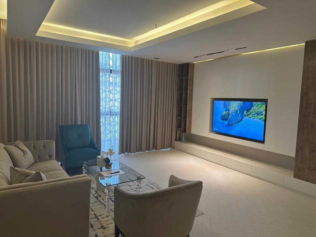 a living room with a couch and a tv on a wall at شقق فندقيه رسال in Ar Riyāḑ