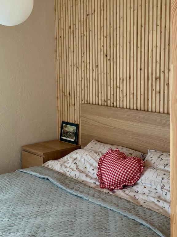 a bed with a red and white pillow on it at Malūno namai 2 in Palanga