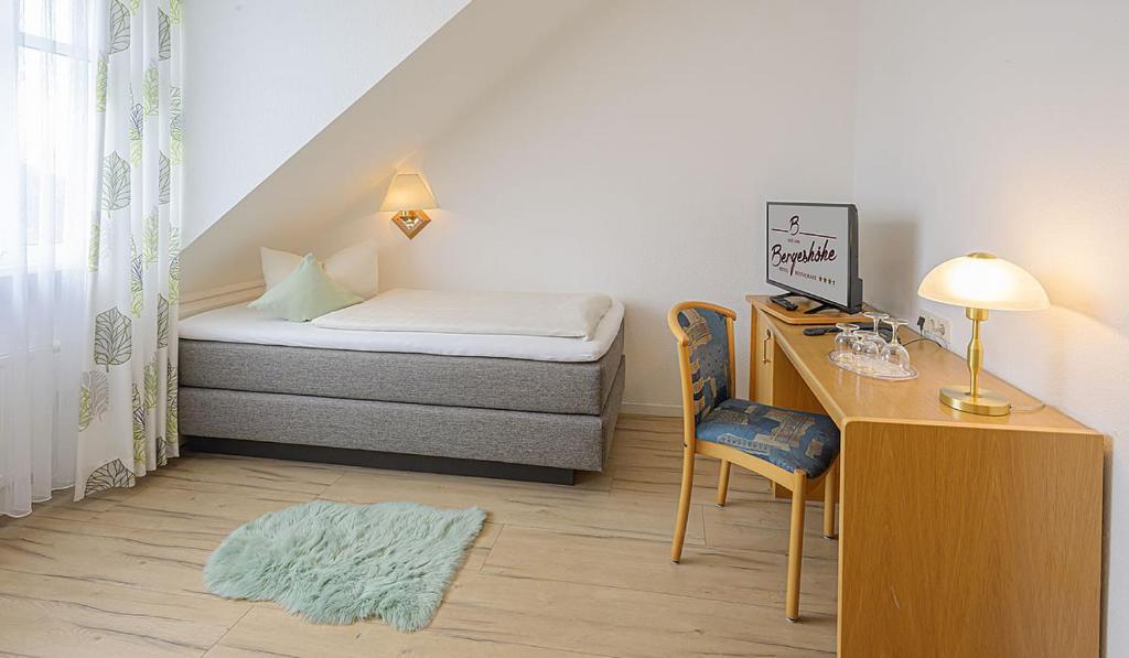 a small room with a bed and a desk at Hotel Restaurant Bergeshöhe in Mettingen